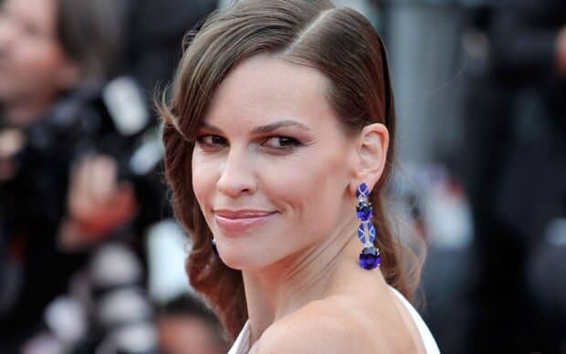 Hilary Swank smiles elegantly at an event showcasing her blue earrings, 2K Desktop Wallpaper