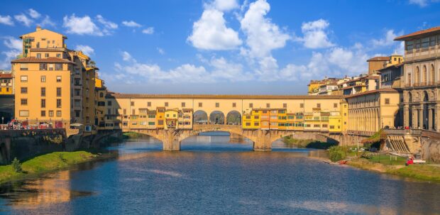 The historic Ponte Vecchio bridge in Florence spans the Arno River with colorful buildings, 2K Desktop Wallpaper