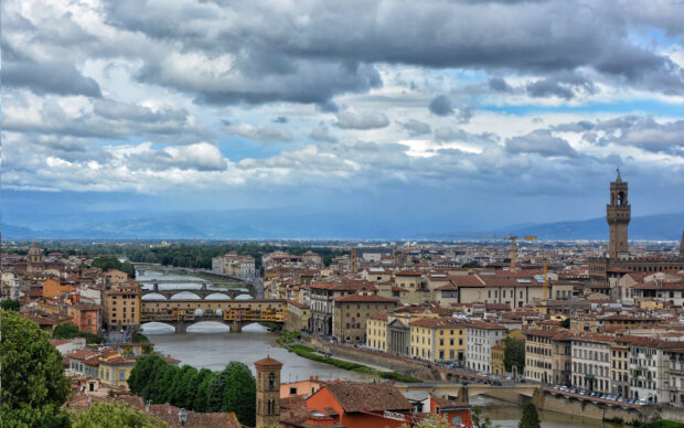 This image shows the Ponte Vecchio bridge and surrounding cityscape under a cloudy sky, HD Desktop Wallpaper