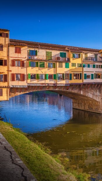 The historic Ponte Vecchio has colorful windows and reflects on the river, HD Mobile Wallpaper
