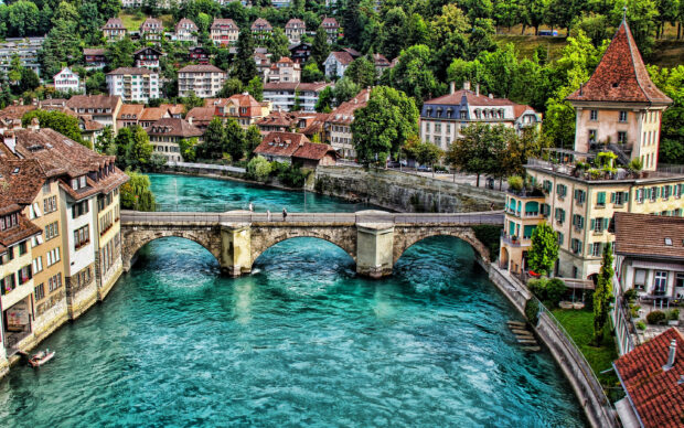 The River Aare flows through a picturesque Swiss town with old buildings and a stone bridge, 2K Desktop Wallpaper
