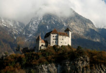 A historic castle sits among autumn trees with snowy mountains in the background in Liechtenstein Wallpapers, HD Desktop Wallpaper