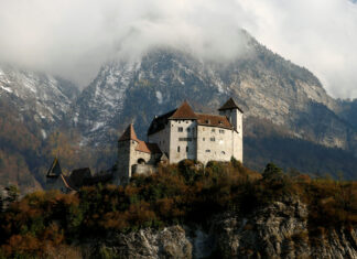 A historic castle sits among autumn trees with snowy mountains in the background in Liechtenstein Wallpapers, HD Desktop Wallpaper
