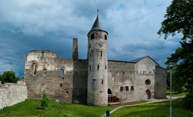 The Estonia wallpapers show an ancient stone castle tower surrounded by greenery and blue sky, 2K Desktop Wallpaper