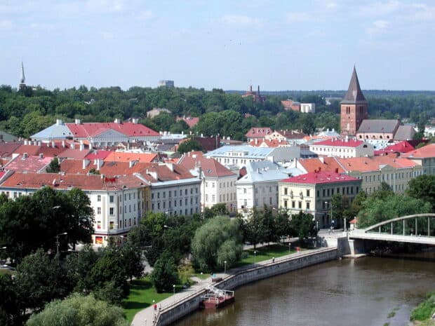 The Estonia cityscape features a river and historic buildings under clear skies, HD Desktop Wallpaper