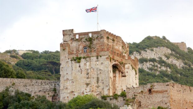 A historic fortress with a British flag is standing tall among greenery in Gibraltar, 2K Desktop Wallpaper