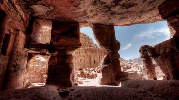 The ancient rock formations at Petra Jordan can be seen from a cave opening under the sun, 2K Desktop Wallpaper