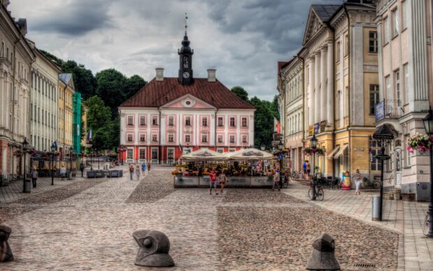 The historic town square features classic architecture and people walking under cloudy skies in Estonia Wallpapers, 2K Desktop Wallpaper