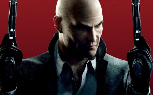 The Hitman game character holds dual pistols with a serious expression, HD Desktop Wallpaper