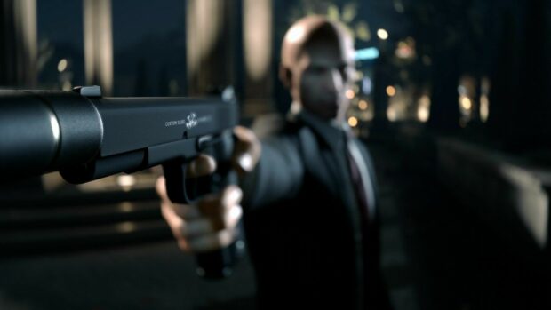 A hitman is aiming a silenced pistol in an urban night setting with blurred background, HD Desktop Wallpaper