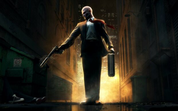 A hitman stands in a dark alley holding a gun and briefcase with city lights behind, HD Desktop Wallpaper