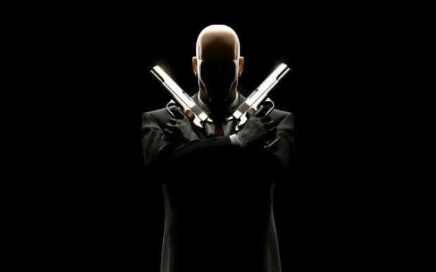 A Hitman game character with crossed pistols in a dark setting, 2K Desktop Wallpaper