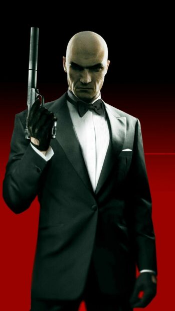 A serious Hitman game character holds a silenced pistol while wearing a tuxedo against a red background, HD Phone Wallpaper