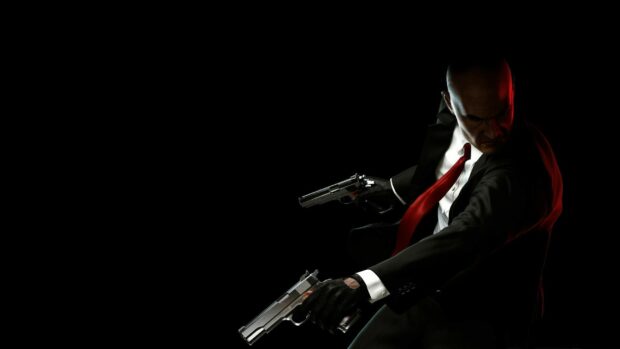 A man in a suit with a red tie holding two pistols in a dark setting, HD Desktop Wallpaper