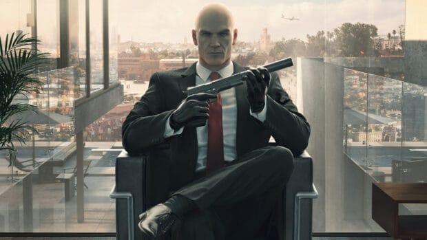 A hitman from the Hitman game holding a silenced pistol and sitting in a chair, 4K Desktop Wallpaper