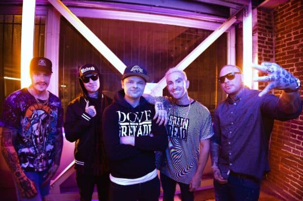 The Hollywood Undead band poses together in a vibrant urban setting with colorful lighting, 2K Desktop Wallpaper