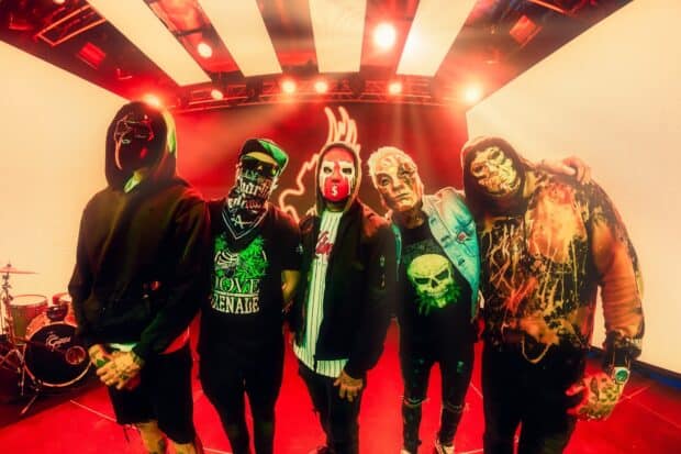 The Hollywood Undead band members wearing distinct masks pose on stage with red lighting, HD Desktop Wallpaper