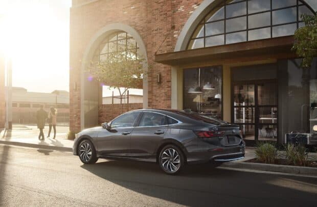 A Honda Insight is parked on the street beside a brick building with arched windows during sunset, HD Desktop Wallpaper