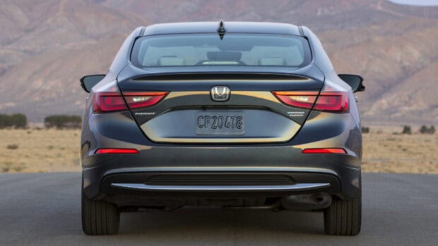 A dark blue Honda Insight showcases its rear view on an open road with mountains in the background, HD Desktop Wallpaper