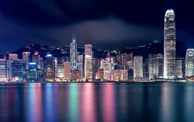 The Hong Kong skyline displays illuminated skyscrapers reflecting on the water at night, 2K Desktop Wallpaper