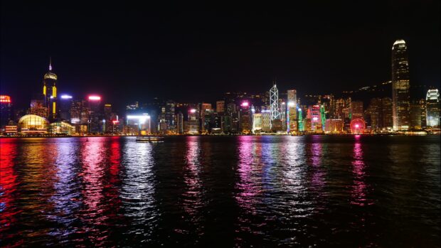 The Hong Kong skyline shows bright lights reflecting over the water under a dark sky, 4K Desktop Wallpaper