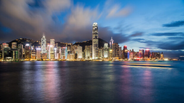 The Hong Kong skyline shows glowing buildings and skyscrapers by the water at night, HD Desktop Wallpaper