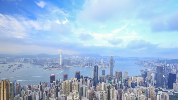 The Hong Kong skyline features numerous skyscrapers under a bright blue sky, 4K Desktop Wallpaper