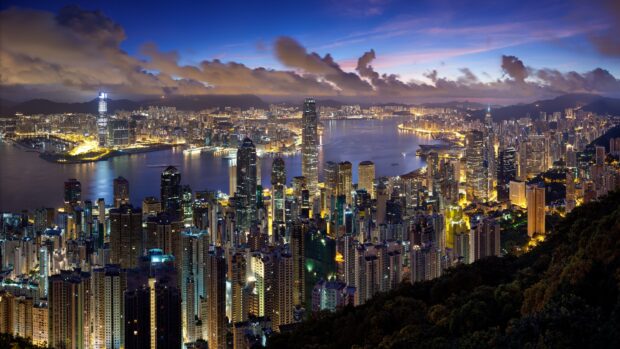 The Hong Kong skyline shows illuminated skyscrapers by the waterfront under a twilight sky, 4K Desktop Wallpaper