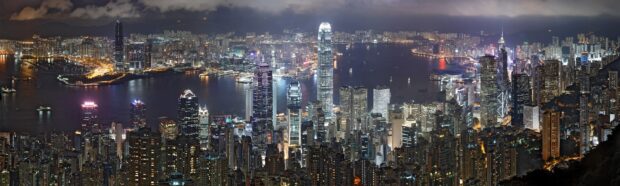 The Hong Kong skyline at night shows illuminated skyscrapers and harbor lights across the city, 2K Desktop Wallpaper
