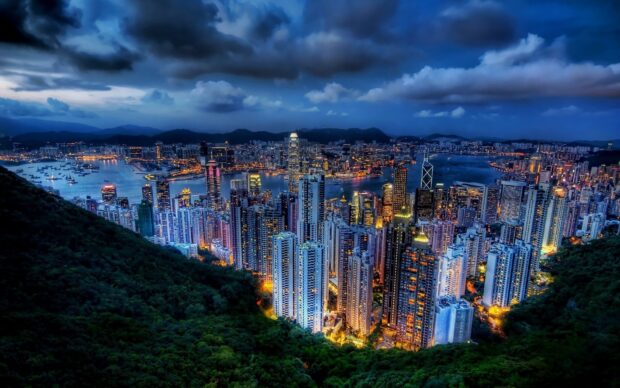 The Hong Kong skyline shows a vibrant cityscape with illuminated skyscrapers and harbor at night, HD Desktop Wallpaper