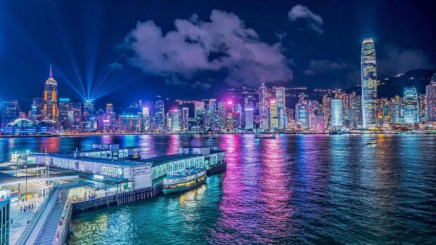 The vibrant Hong Kong skyline lights reflect on the water under a cloudy night sky, HD Desktop Wallpaper