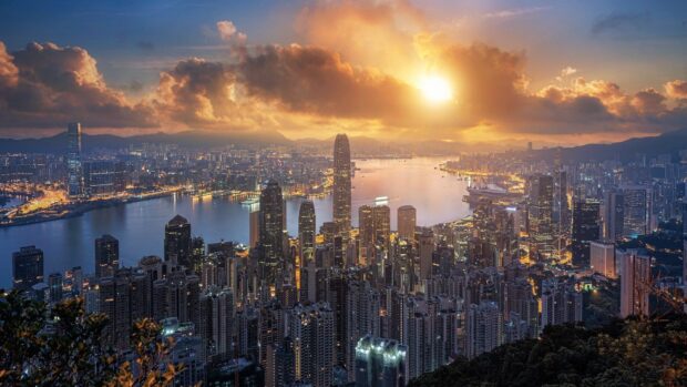 A beautiful Hong Kong skyline captures the sun setting over the city and harbor, HD Desktop Wallpaper