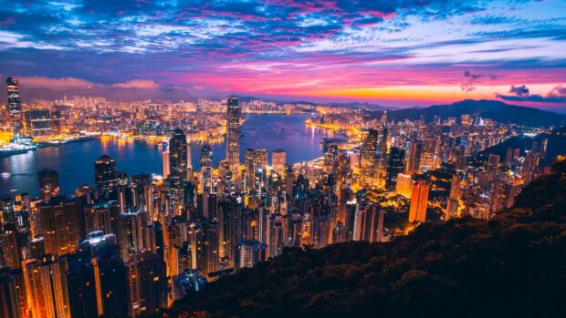 The Hong Kong skyline glows brilliantly against a colorful sunset sky, 2K Desktop Wallpaper