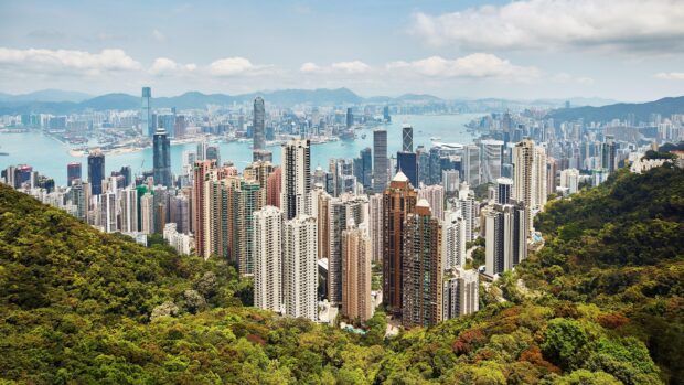 The Hong Kong skyline shows a mix of modern skyscrapers and natural greenery by the harbor, 4K Desktop Wallpaper
