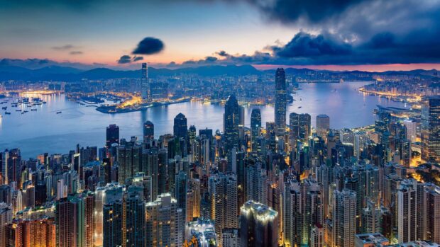 The Hong Kong skyline showcases a breathtaking view with illuminated skyscrapers and evening lights, HD Desktop Wallpaper
