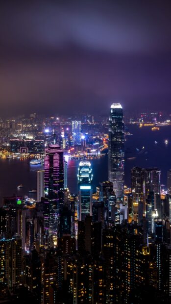The Hong Kong skyline shows illuminated skyscrapers and busy harbor at night, 4K Phone Wallpaper