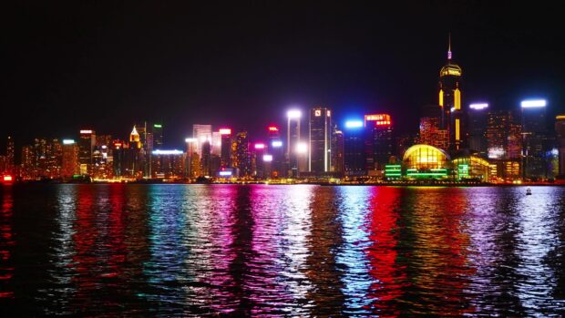 The Hong Kong skyline displays colorful lights reflecting on the water at night, 4K Desktop Wallpaper