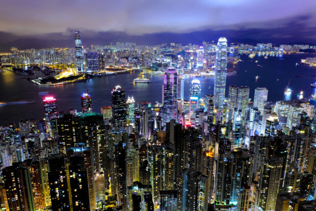 The Hong Kong skyline displays a vibrant cityscape filled with illuminated skyscrapers and a busy harbor at night, 2K Desktop Wallpaper