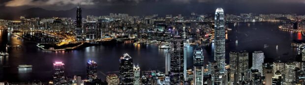 The Hong Kong skyline illuminates the night with tall buildings and reflections in the water, 4K Desktop Wallpaper