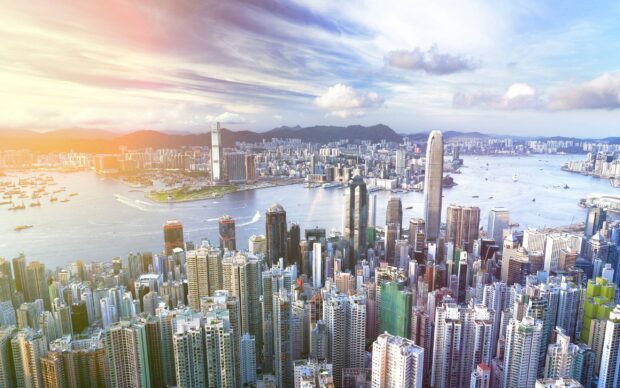 The Hong Kong skyline features towering skyscrapers and a bright sky over the harbor, 2K Desktop Wallpaper