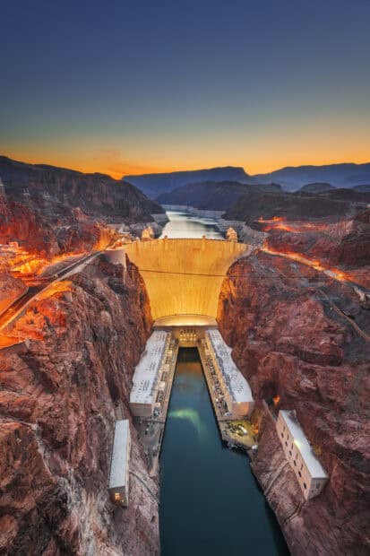 The Hoover Dam stands illuminated at sunset with surrounding canyon and river, HD Desktop Wallpaper