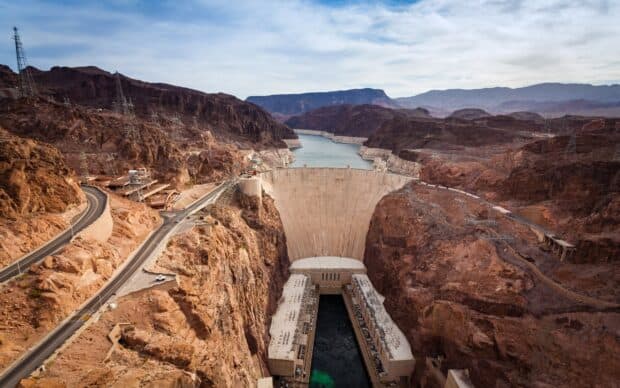 The Hoover Dam holds back the river between rocky mountains under a cloudy sky, 2K Desktop Wallpaper