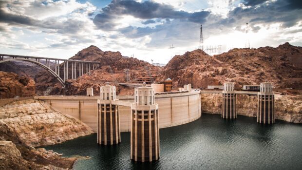 The Hoover Dam stands between rocky hills under a cloudy sky with water below, 4K Desktop Wallpaper