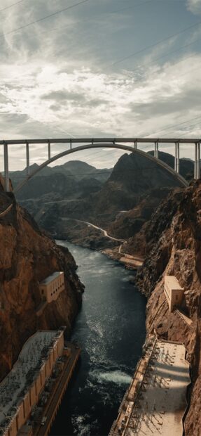 The Hoover Dam showcases the river flowing between rocky cliffs under a bridge, 2K Mobile Wallpaper