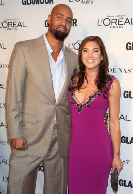 Hope Solo poses with a man dressed in a suit at a Glamour event, HD Mobile Wallpaper