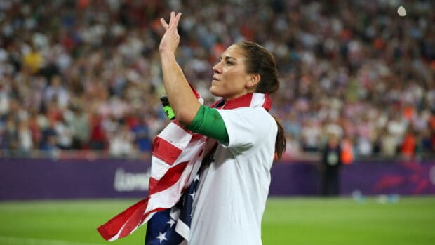 Hope Solo is waving a flag during a soccer match in front of a cheering crowd, 2K Desktop Wallpaper