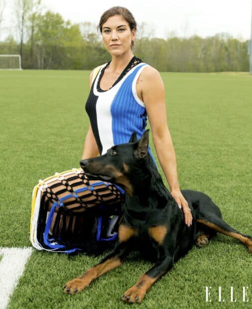 Hope Solo sitting on grass with a large Doberman dog by her side, HD Desktop Wallpaper