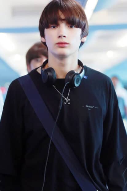 Huening Kai wears black with headphones around his neck in a casual setting, HD Mobile Wallpaper