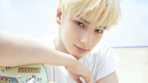 A close up portrait of Huening Kai with blonde hair resting on his arm, 4K Desktop Wallpaper