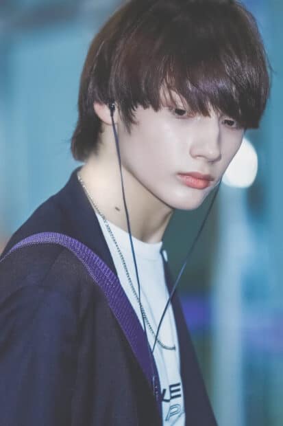 A close up portrait of Huening Kai wearing earphones and looking down, HD Phone Wallpaper